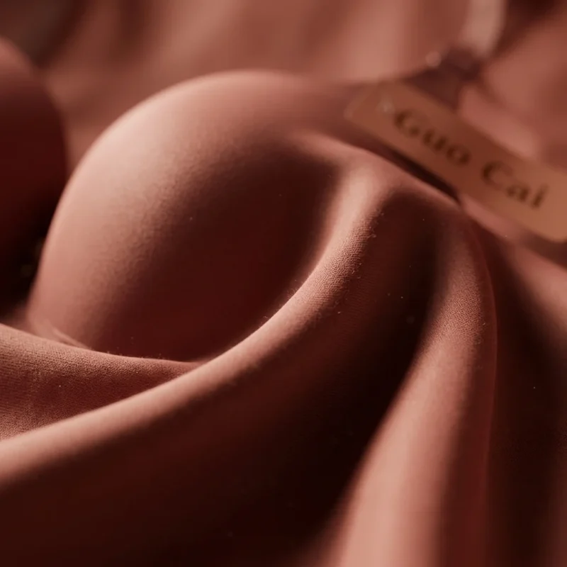 Close-up macro photography of luxurious folded silk fabric and delicate black lace in a warm dusty rose color for The Silk Edit campaign.